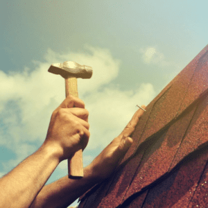 A person hammering a nail in the roof